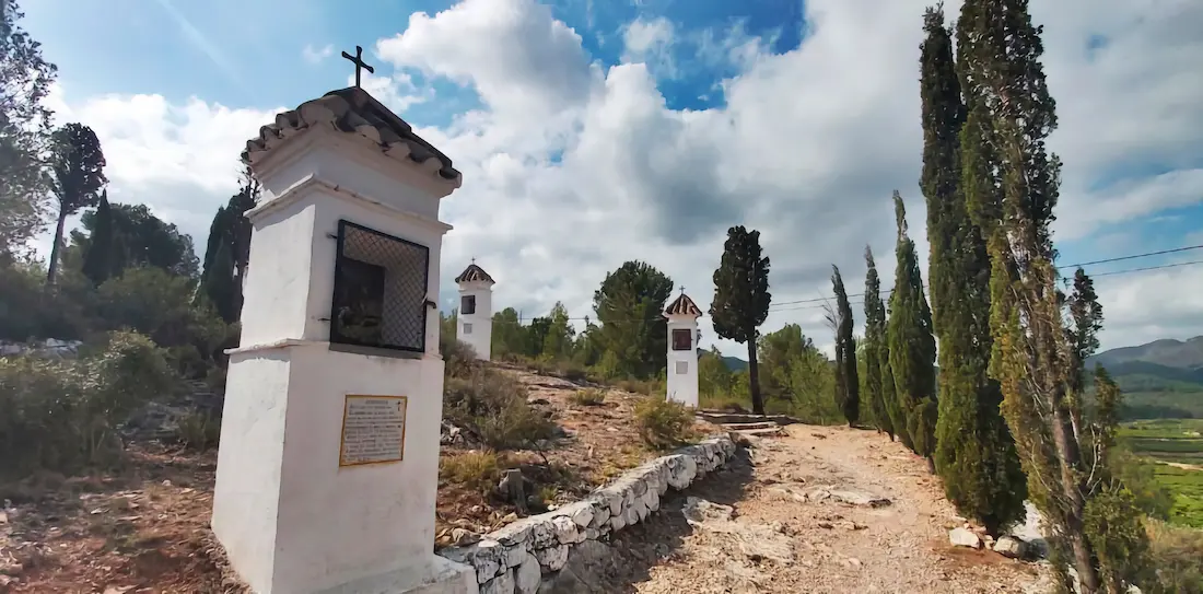 Capillas blancas de las estaciones del Vía Crucis flanqueadas por cipreses en el camino del Calvario de Onda