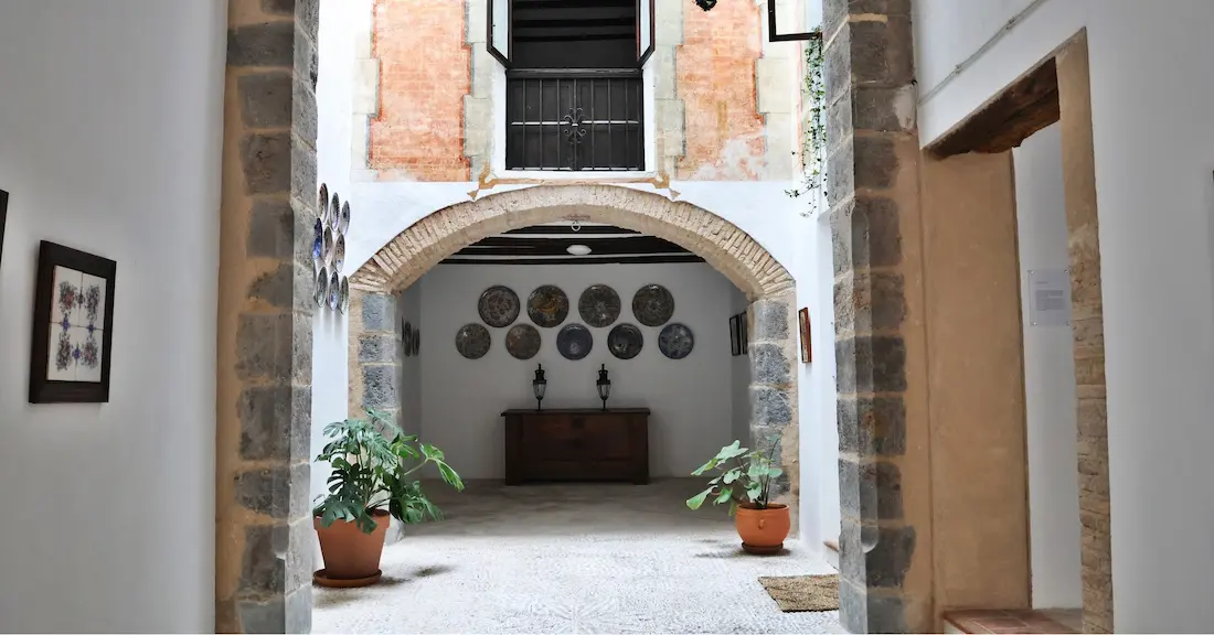 Interior courtyard of Casa de Dalt with stone arch, ceramic plates on the wall and plants, historic quarter of Onda