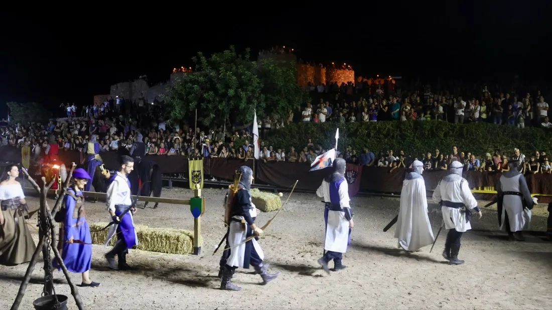 Soldados y arqueros desfilando de noche con el castillo de Onda iluminado al fondo durante la Feria Medieval