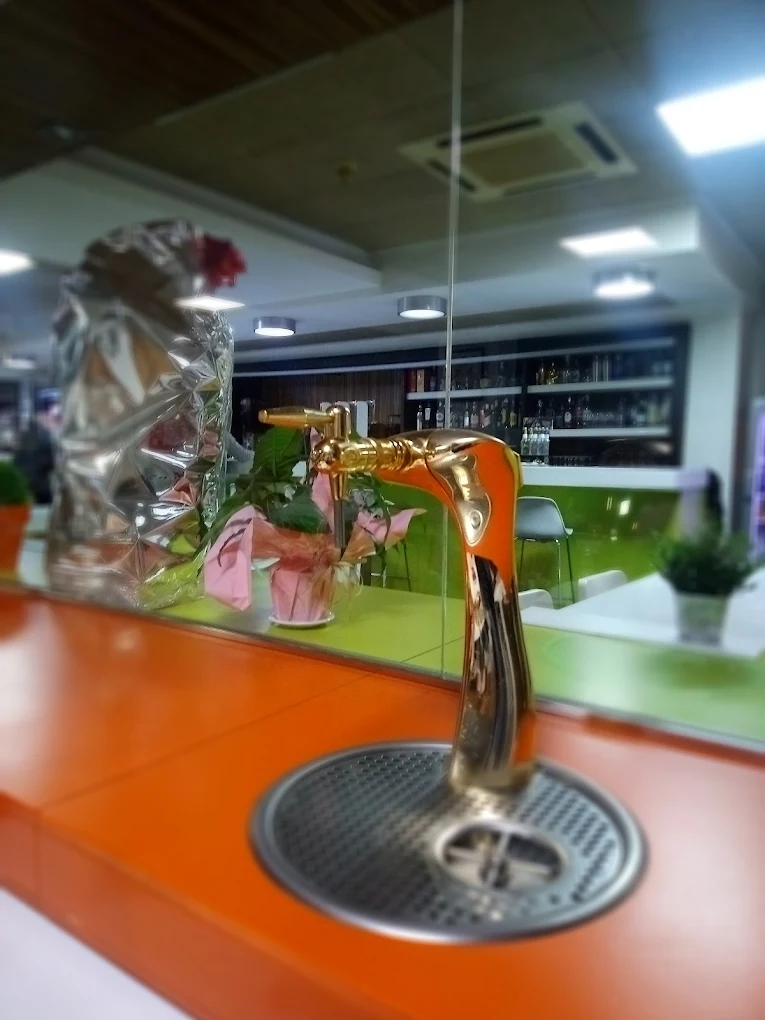 Grifo de cerveza dorado sobre la barra naranja del bar