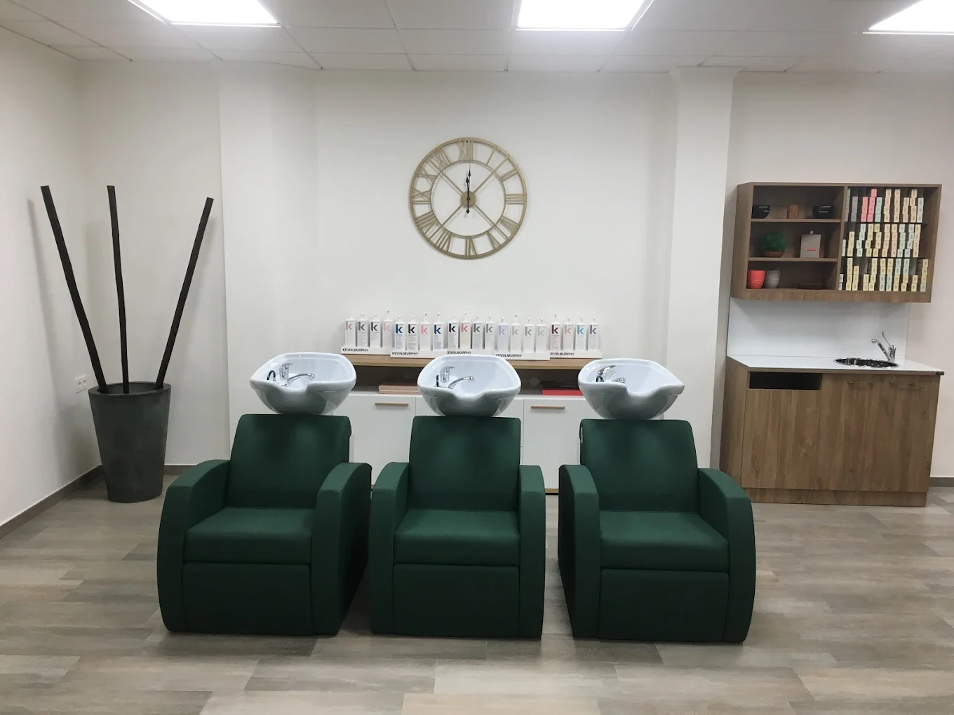 Zona de lavado con sillones verdes y productos Kevin Murphy