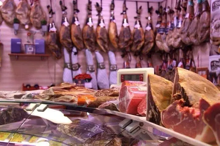 Jamones colgados y mostrador de charcutería en Casa Paco, Onda