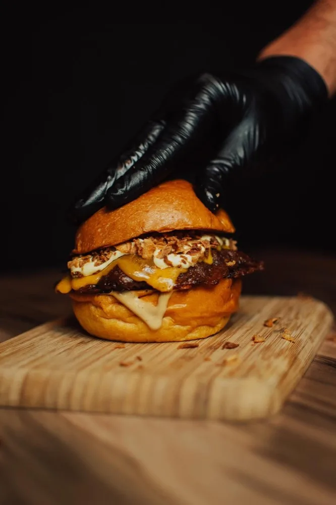Smash burger de Delicious Burger servida sobre tabla de madera