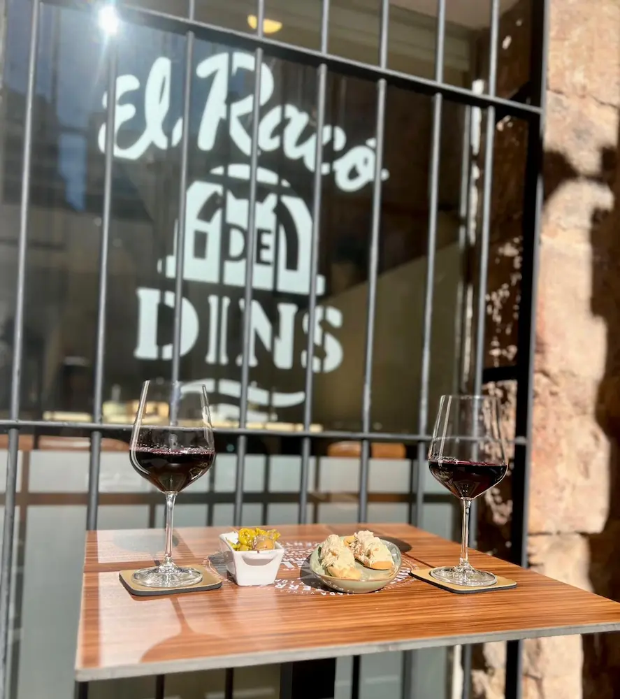 Terraza de El Racó de Dins con dos copas de vino tinto y logotipo en la vidriera, Plaça de l'Almudí, Onda