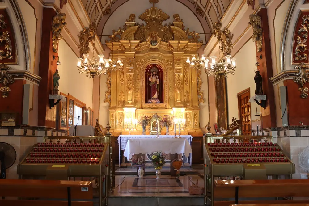 Interior de la ermita del Santísimo Salvador de Onda con el retablo dorado barroco de 1734 y velas votivas