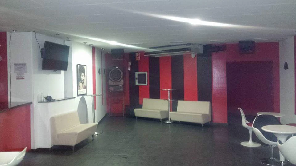 Sala interior de El Flamenkito con sofás blancos y decoración roja y negra
