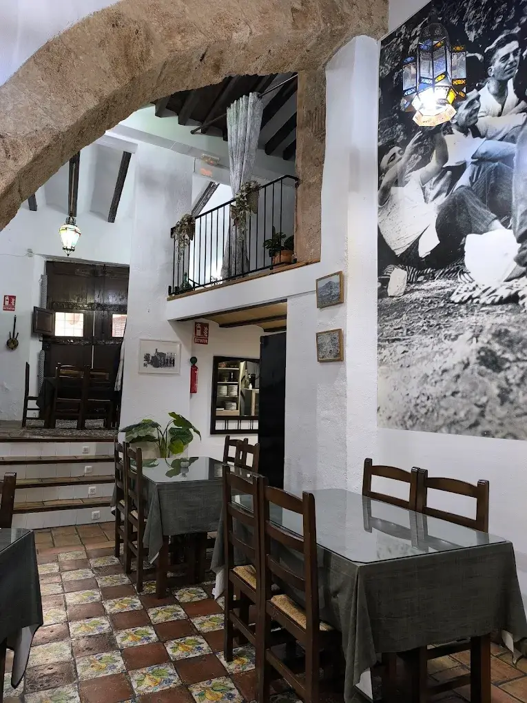Interior de La Cantina con arco de piedra, balcón de forja y suelo de azulejos valencianos