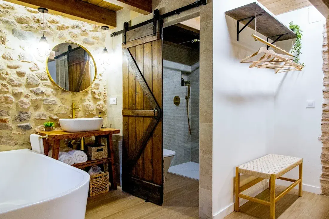 Baño amplio con puerta estilo granero en Refugi dels Somnis