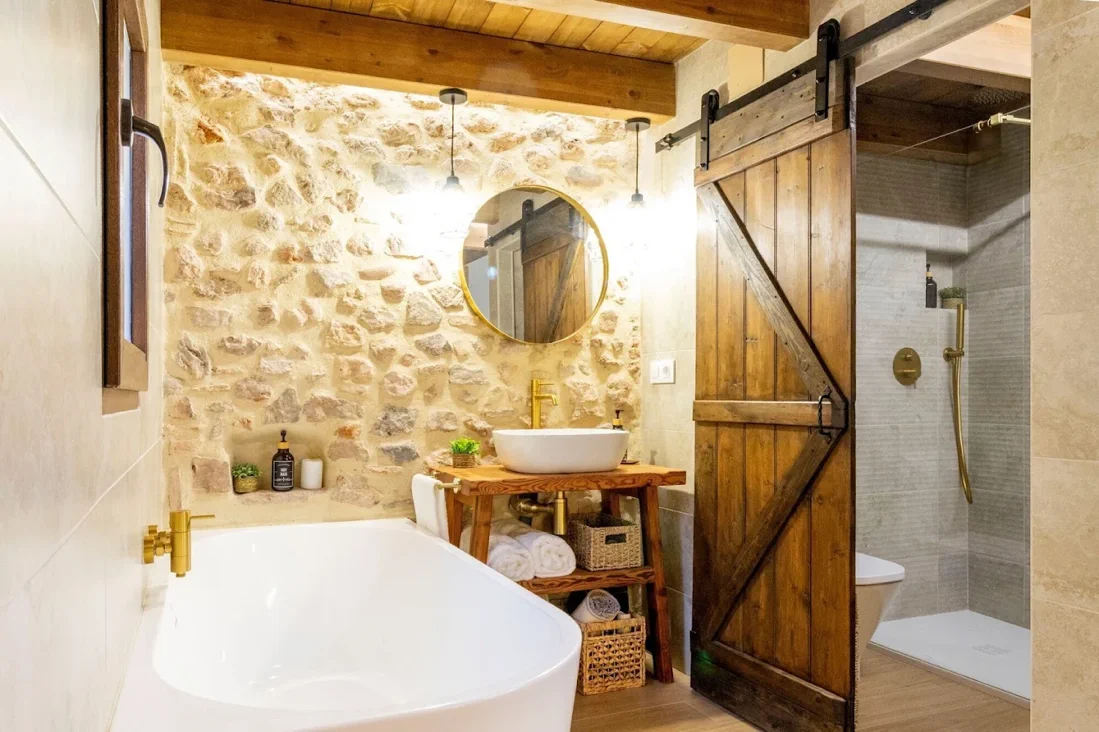 Baño con pared de piedra y bañera exenta en Refugi dels Somnis