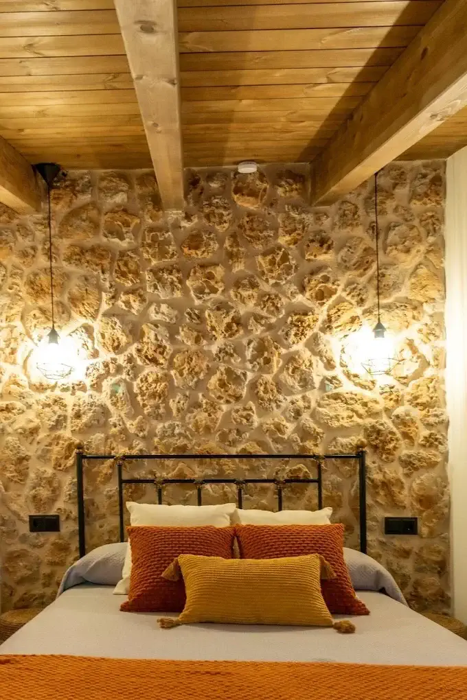 Cabecero de forja con pared de piedra en Refugi dels Somnis