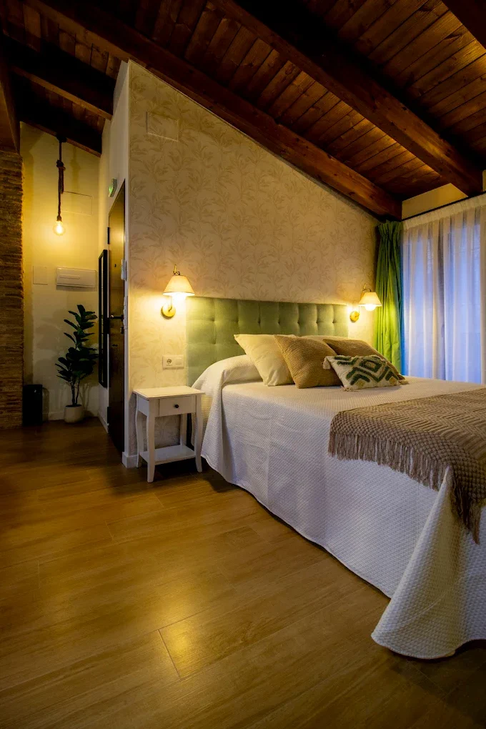 Habitación con cabecero verde y techo de madera en Refugi dels Somnis