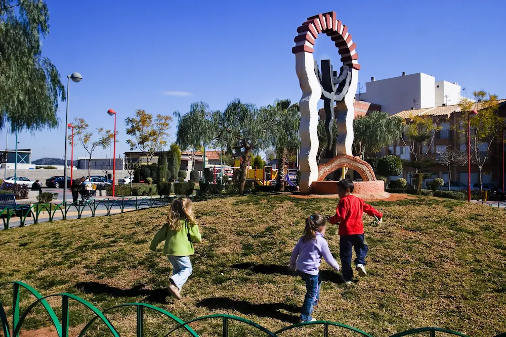 Niños jugando en el Parque de las Tres Culturas de Onda con la escultura Tolerantia al fondo
