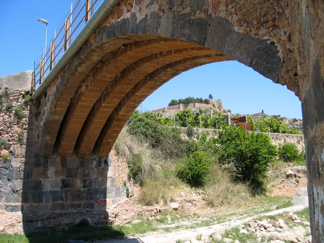 Arco interior del puente medieval del Sonella enmarcando el castillo de Onda